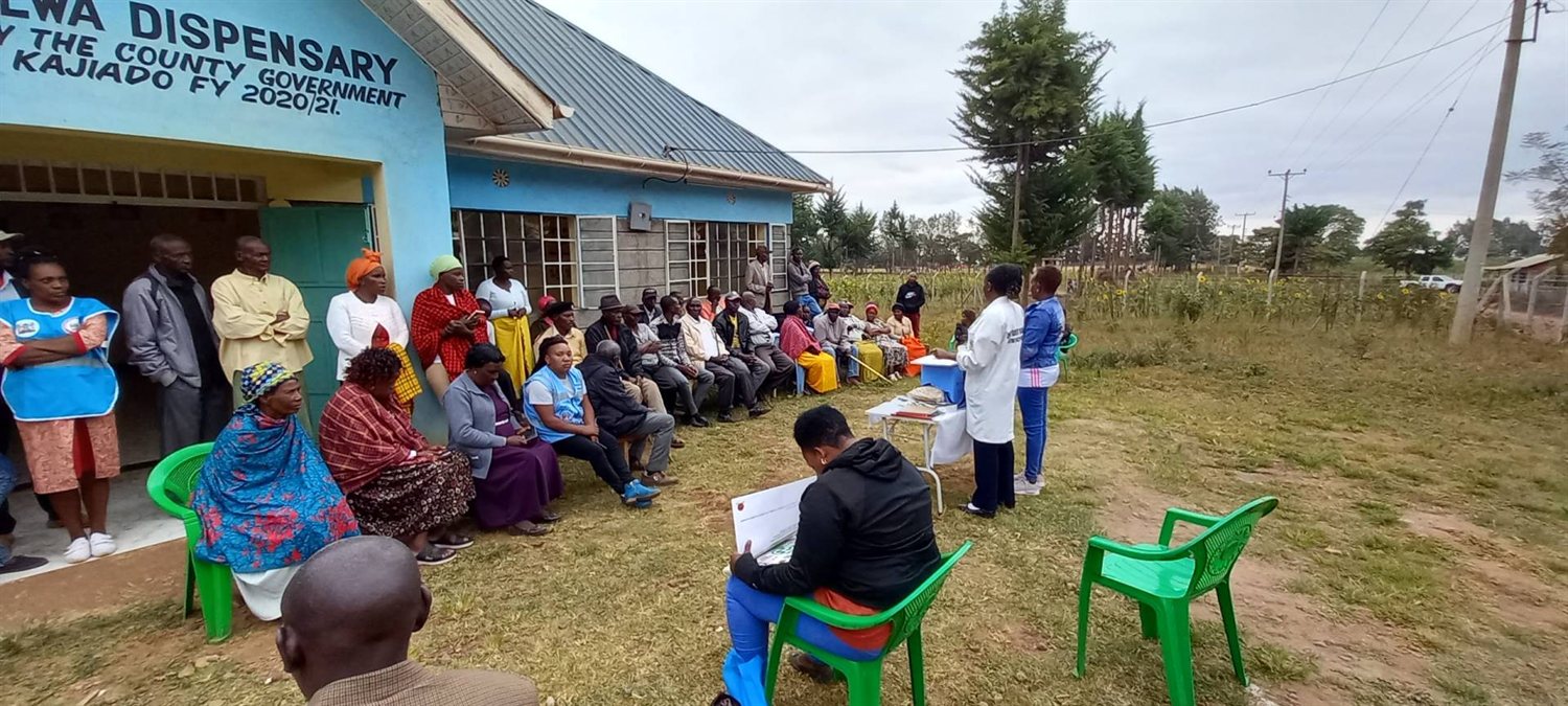 Community members gather outside a dispensary for a health education dialogue