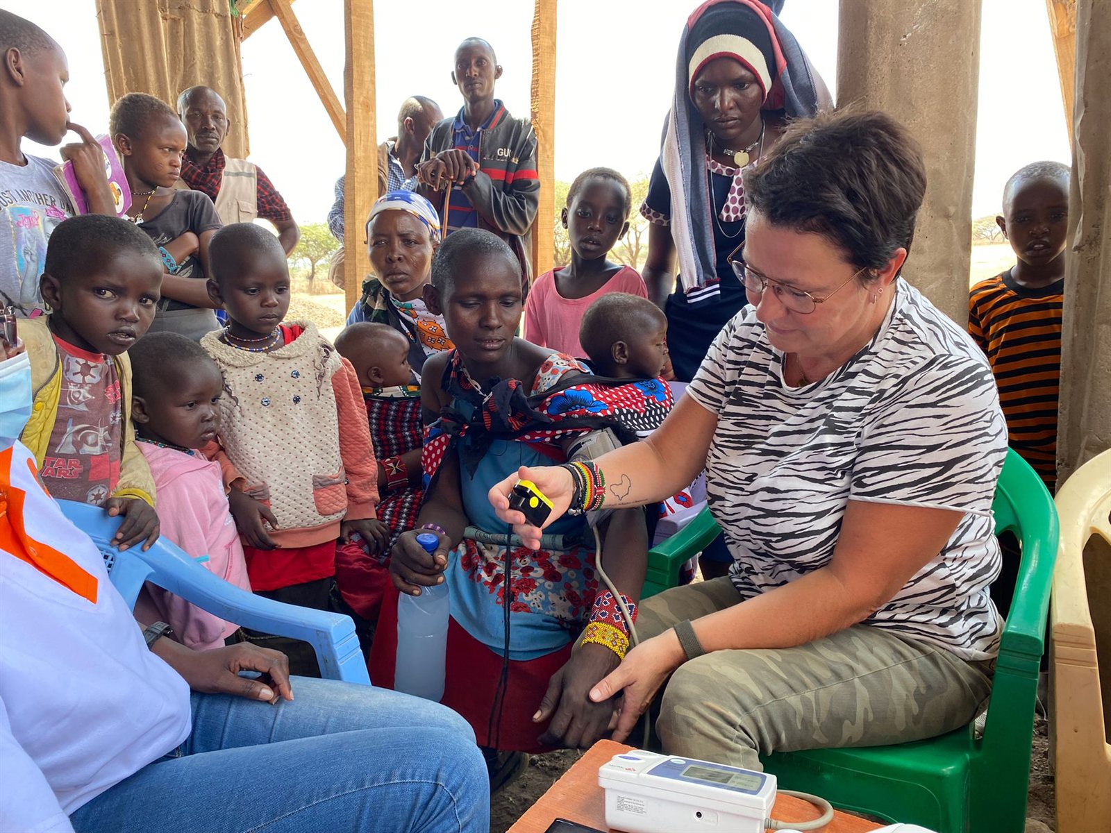 A clinician taking a patient's blood pressure while families wait at an Entepesi Kenya outreach