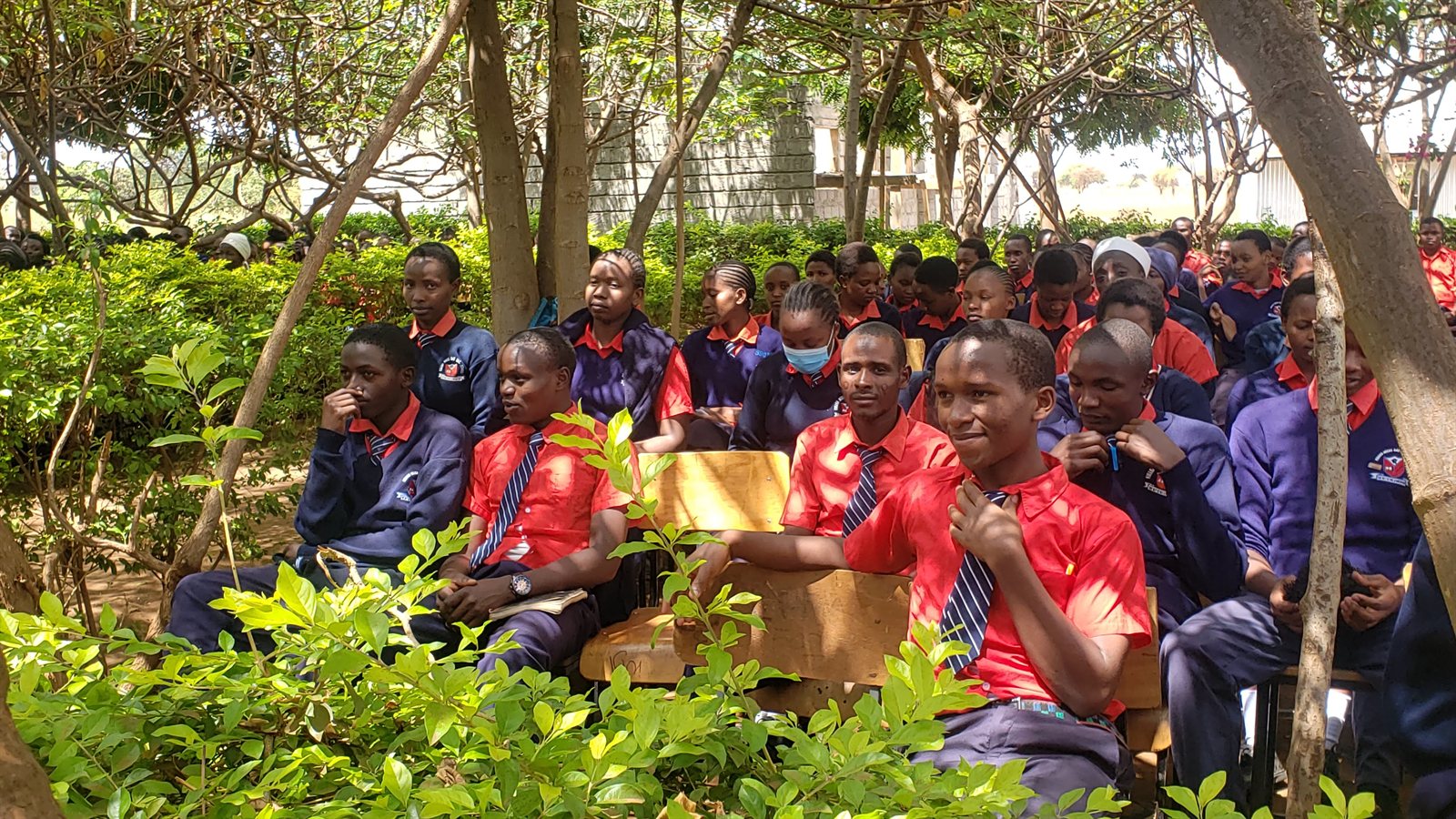 Secondary school students gathered outdoors for a menstrual health education session